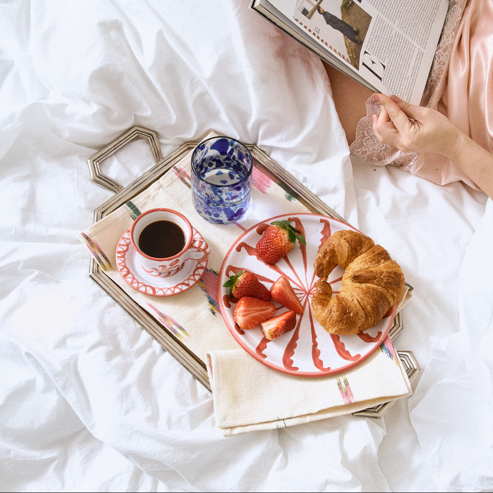 Person lying on a bed with a tray of breakfast food and a newspaper. - lifestyle