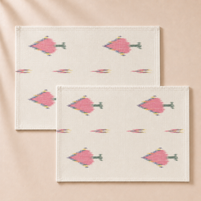 Two white placemats with pink geometric fish pattern on a beige background