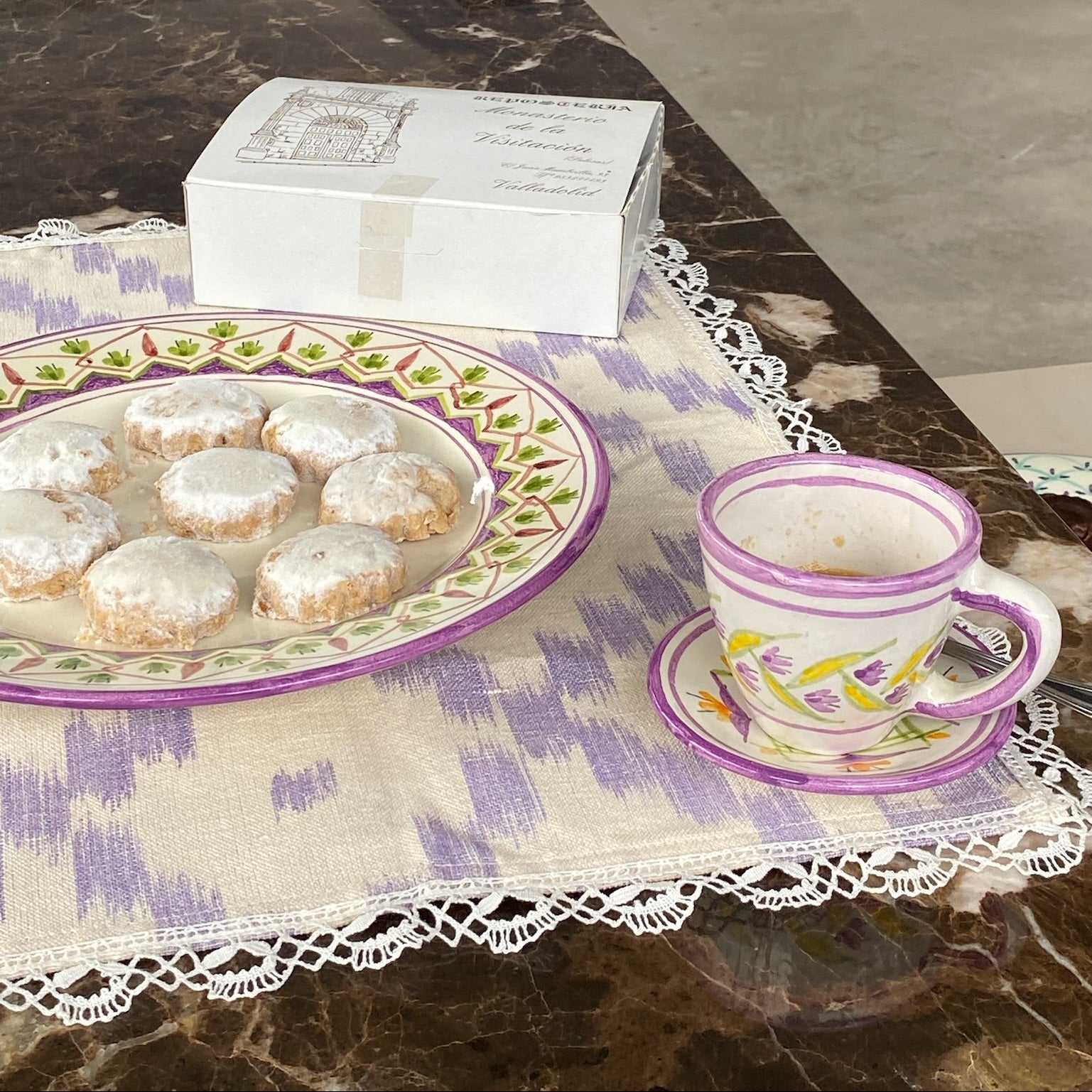 Cookies on a decorative plate with a teacup and saucer on a marble surface - lifestyle