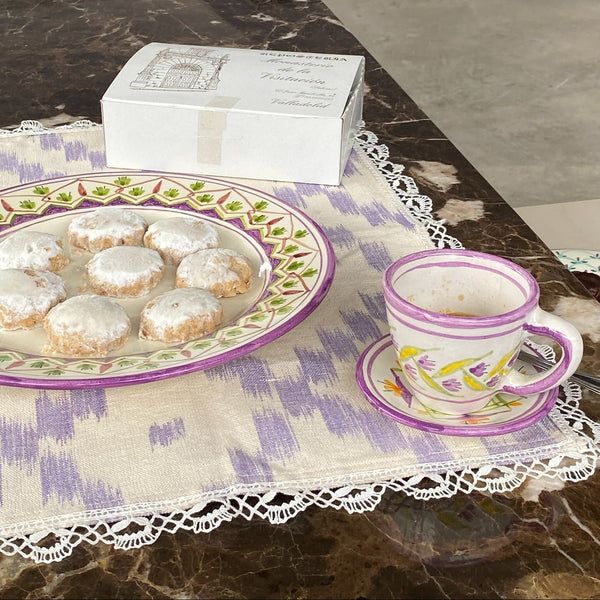 Cookies on a decorative plate with a teacup and saucer on a marble surface - lifestyle