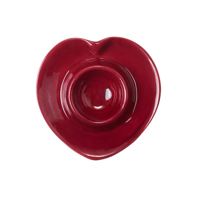 A red heart shaped ceramic egg cup seen from above on a white background.