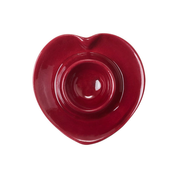 A red heart shaped ceramic egg cup seen from above on a white background.