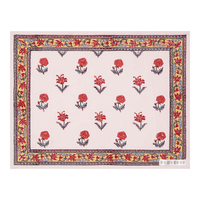 A hand-block printed cotton table mat with a floral pattern in red and yellow on a white background, bordered with a blue and orange design.