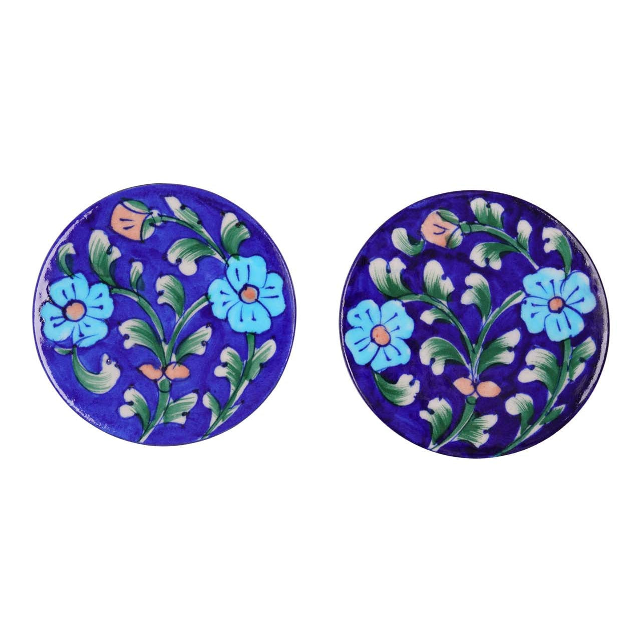 Two round ceramic coasters with a blue background and floral hand-painted patterns in blue, pink, and green.