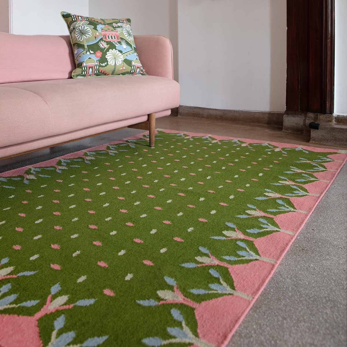 Living room with pink sofa and green and pink flatweave rug.