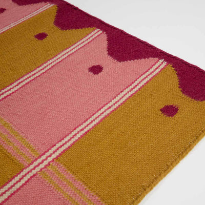 Detail of pink and yellow ladder runner with wavy border and checkered pattern.