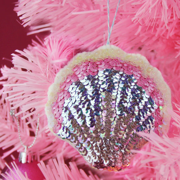 A sequinned scallop ornament on a pink Christmas tree