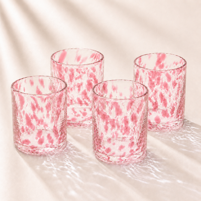 Four pink and clear marbled glass tumblers on a light background