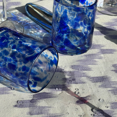 Two blue spotted  glasses tumblers on a patterned tablecloth - lifestyle