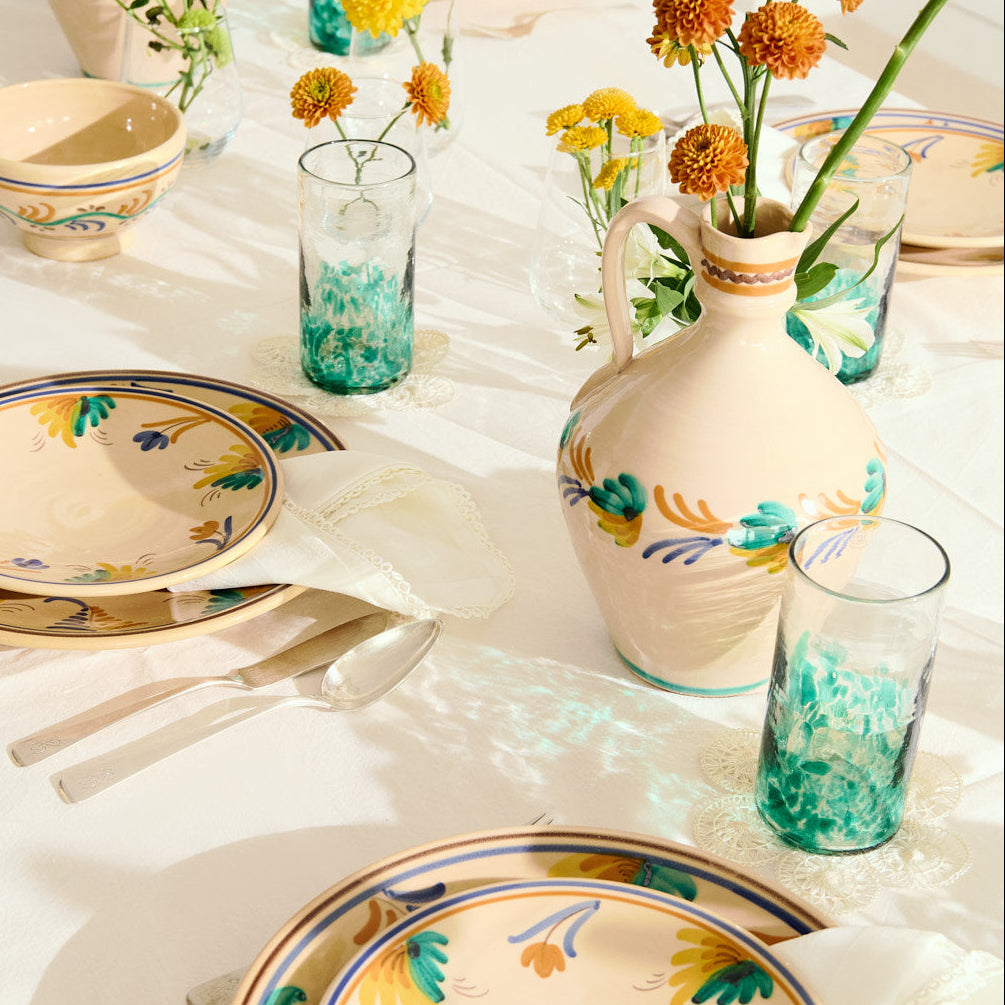 Decorative table setting with floral-patterned plates and vases on a white tablecloth.- lifestyle