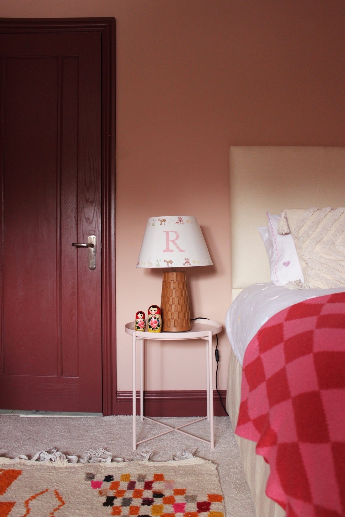 Personalised kids lampshade with woodland animal print and customised initial, styled on a ceramic lamp base in a cosy kids bedroom design with pink walls and playful décor.