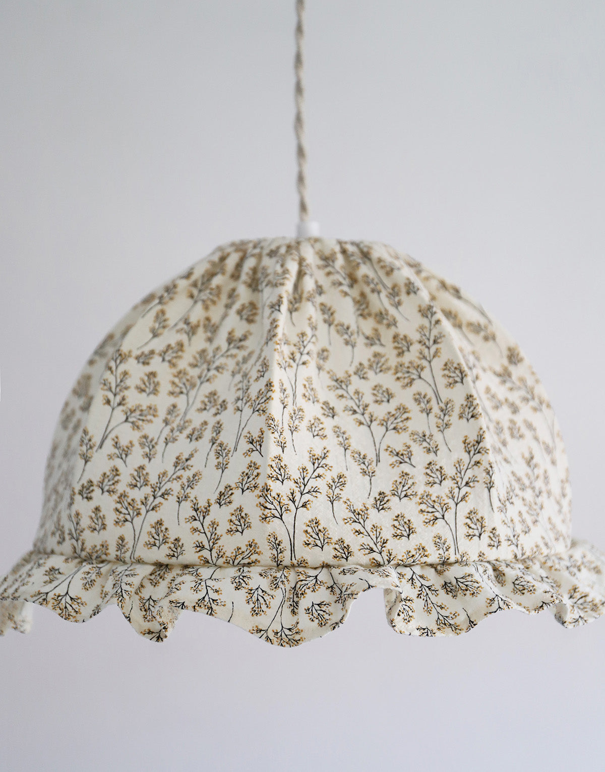 Suspension dôme arrondi en tissu crème ornée d’un motif végétal branching marron clair, avec volants décoratifs et cordelette pour fixation.