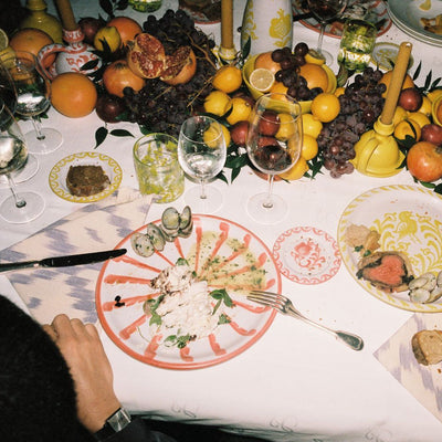Dining table set with plates, cutlery, and a variety of fruits and vegetables. - lifestyle