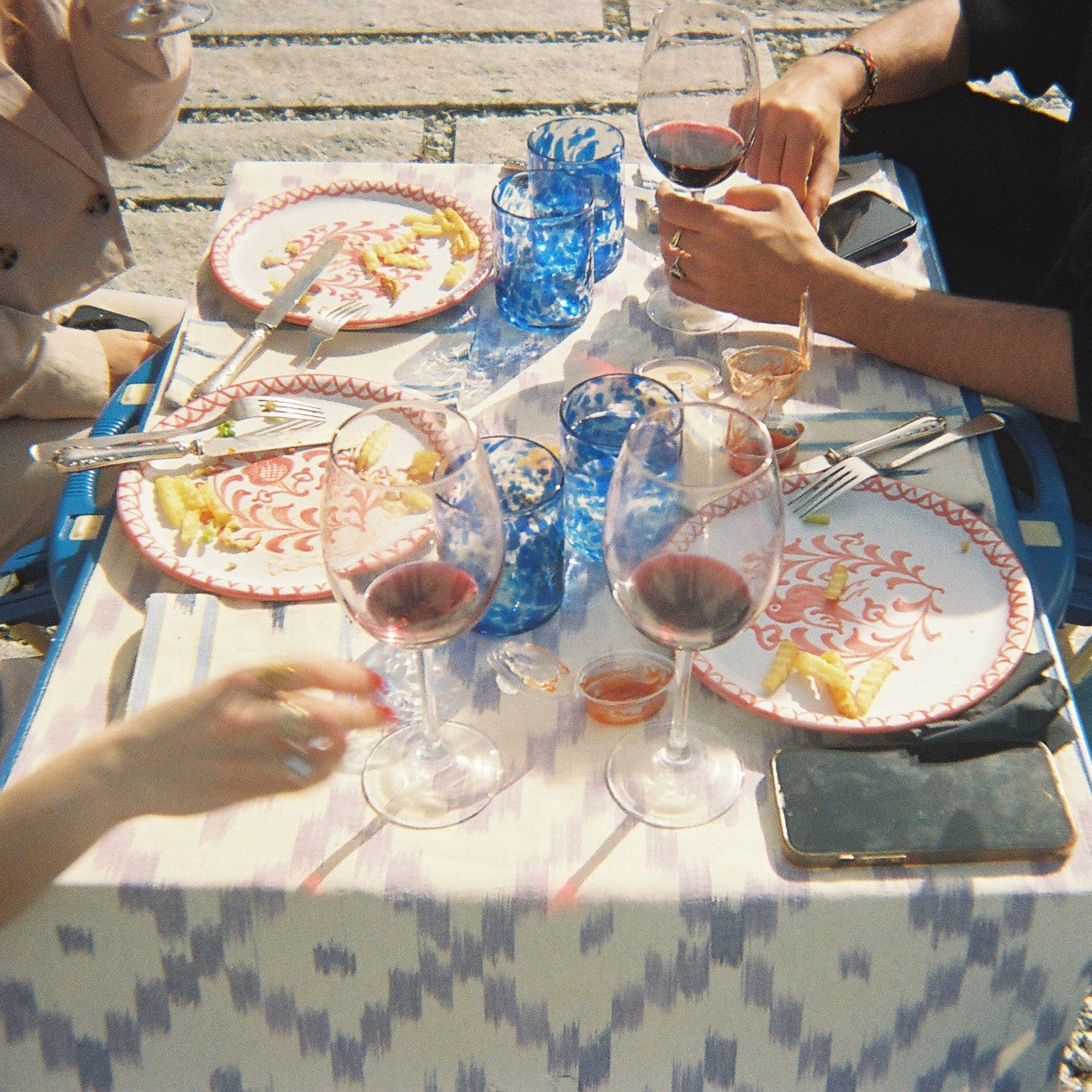 People sitting at a table with wine glasses and plates outdoors on a table runner  - lifestyle