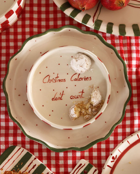 Decorative plate with 'Christmas Calories don't count' text on a red checkered tablecloth.
