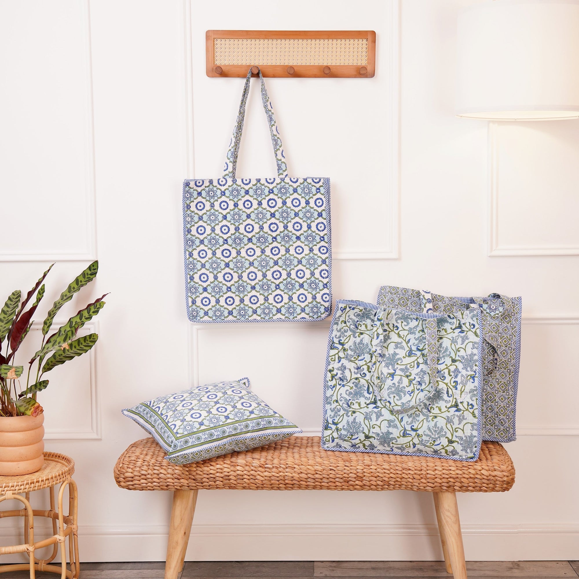A block printed cotton tote bag with contrast trim and a botanical design, another tote with a geometric design and a cushion with a matching geometric design. All in blues and greens