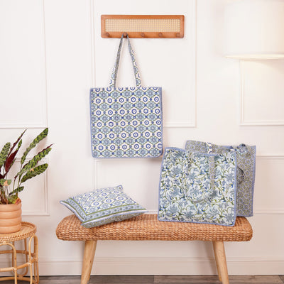 A block printed cotton tote bag with contrast trim and a botanical design, another tote with a geometric design and a cushion with a matching geometric design. All in blues and greens