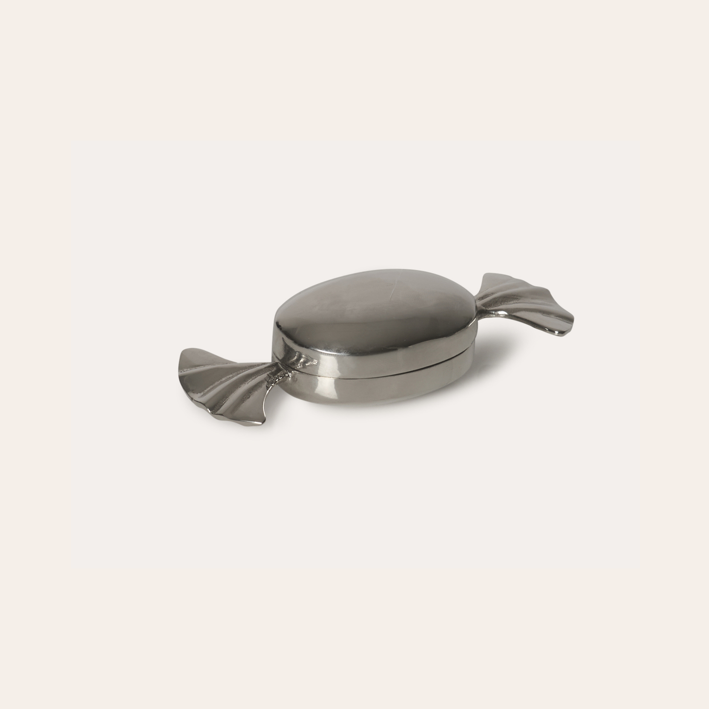 Metallic candy-shaped container on a light gray background