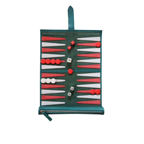A travel backgammon board with a green, white, and red suede playing field, including red and white dice and a strap for carrying.