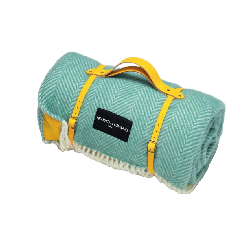 Mint green picnic blanket in wool with a yellow waterproof backing and a yellow leather strap