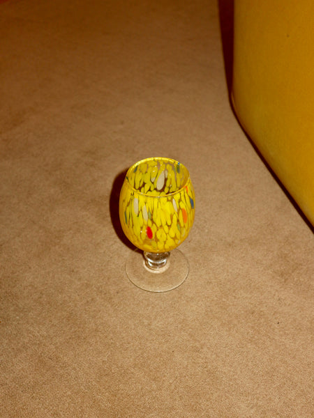 Small glass with yellow pattern on a beige carpet