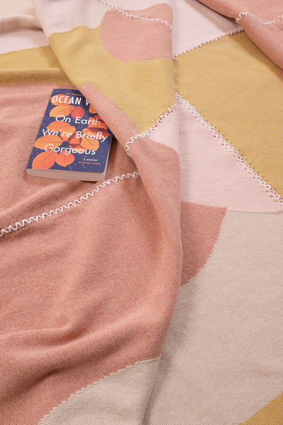 Colorful knit wool blanket with a book titled 'Ocean' on top
