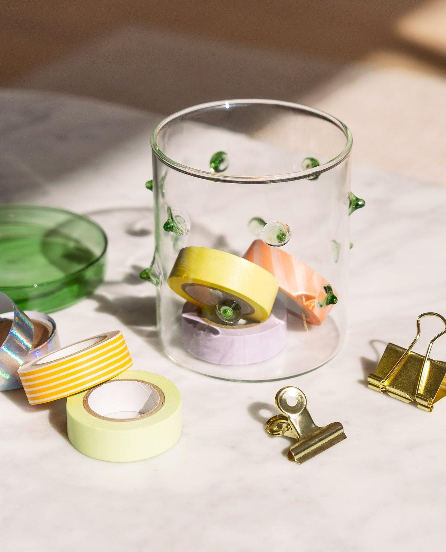 The Agave Glass Container Small by OCTAEVO stores washi tapes and clips on a marble table.