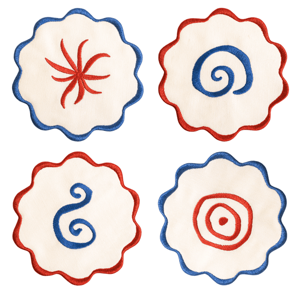 The Amalfi Coasters set by Octaevo features 4 white linen-cotton coasters with blue or red scalloped swirl embroidery.