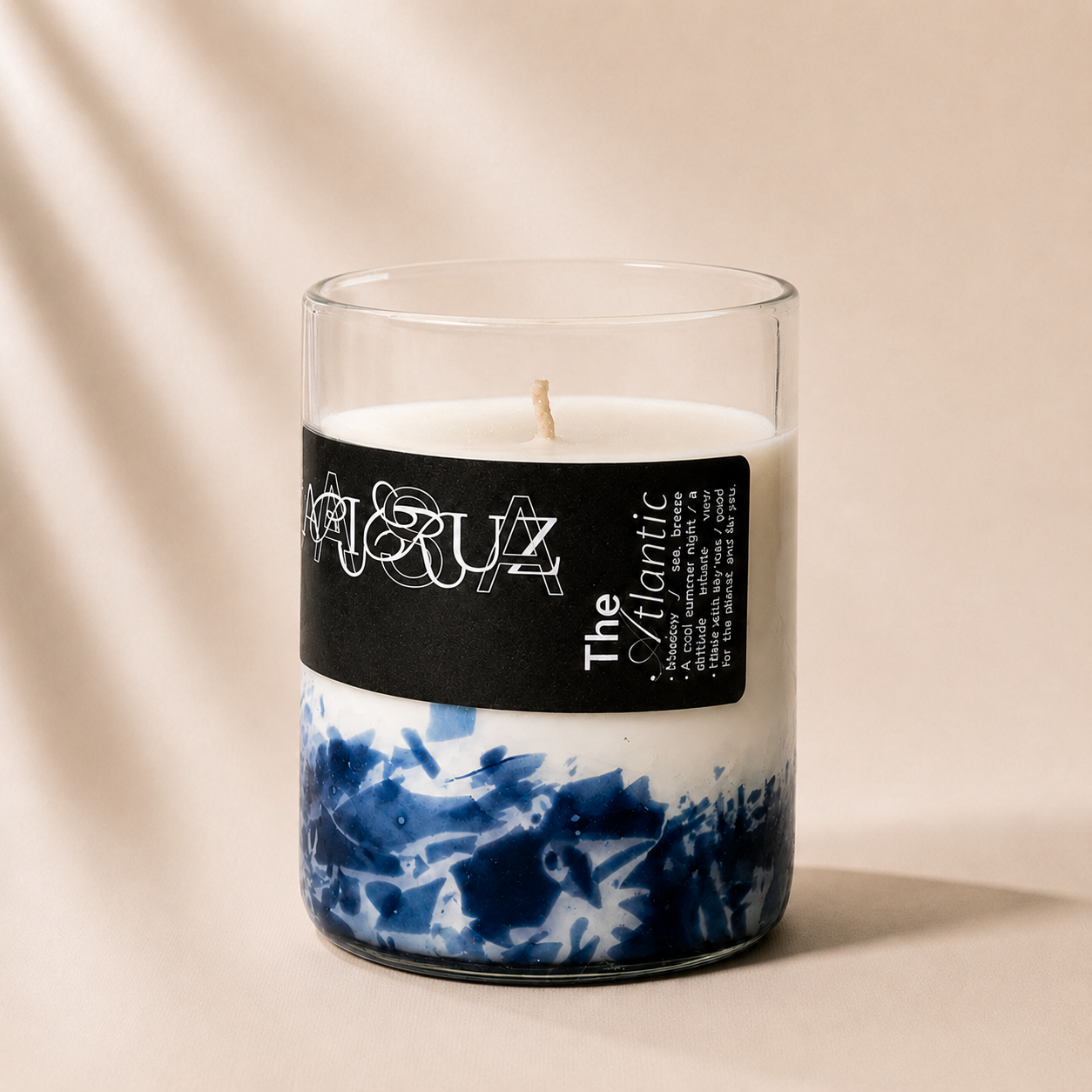 Candle with a blue and white pattern in a glass container on a beige background