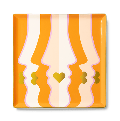The Beso Ceramic Tray by Octaevo features abstract orange faces, gold hearts, and is perfect for a chic gift or tablescape.
