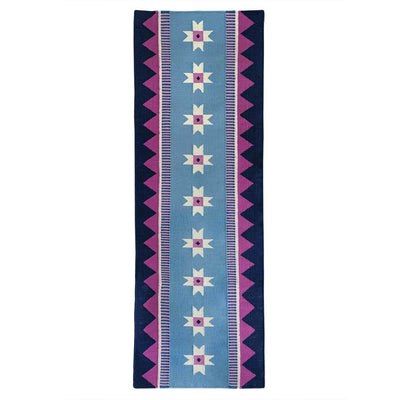 Blue runner rug handwoven from New Zealand wool with a geometric design of star motifs and a pink zig zag border inspired by Victorian tiles. 