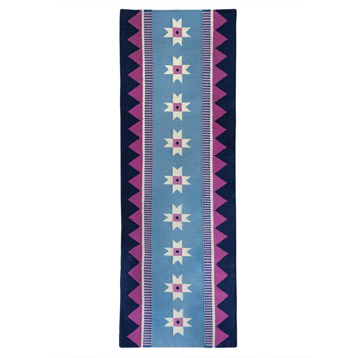 Blue runner rug handwoven from New Zealand wool with a geometric design of star motifs and a pink zig zag border inspired by Victorian tiles. 