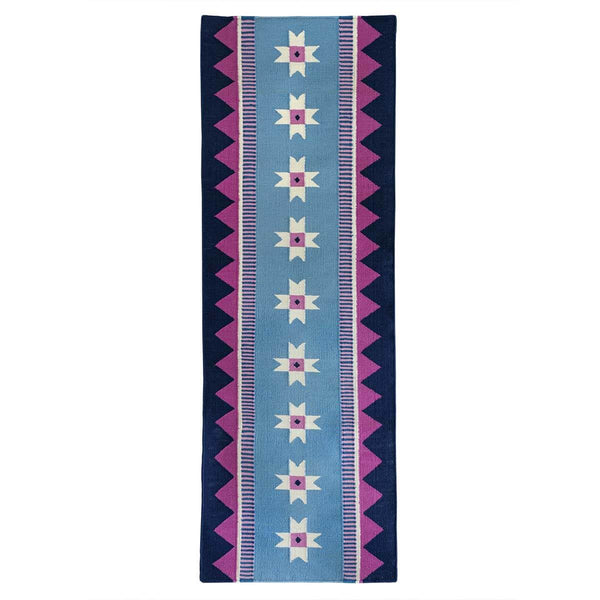 Blue runner rug handwoven from New Zealand wool with a geometric design of star motifs and a pink zig zag border inspired by Victorian tiles. 