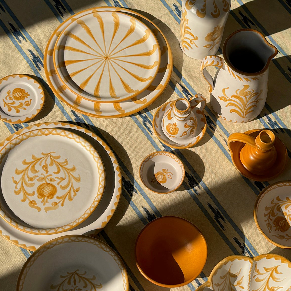 Decorative ceramic tableware with gold patterns on a striped fabric background - lifestyle