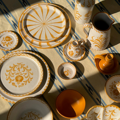 Decorative ceramic tableware with gold patterns on a striped fabric background - lifestyle