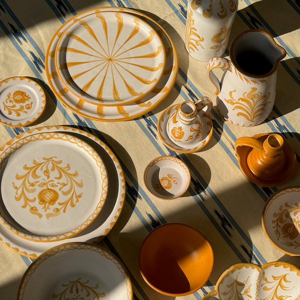 Decorative ceramic tableware with gold patterns on a striped fabric background - lifestyle