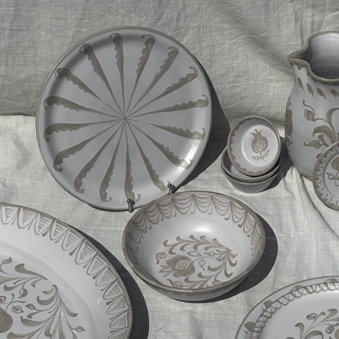 Set of ceramic plates and a pitcher with floral patterns on a textured fabric background - lifestyle