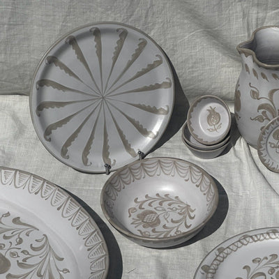 Set of ceramic plates and a pitcher with floral patterns on a textured fabric background - lifestyle