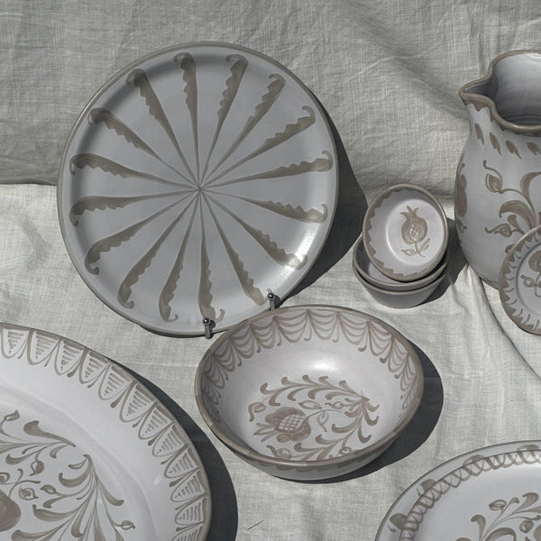 Set of ceramic plates and a pitcher with floral patterns on a textured fabric background - lifestyle