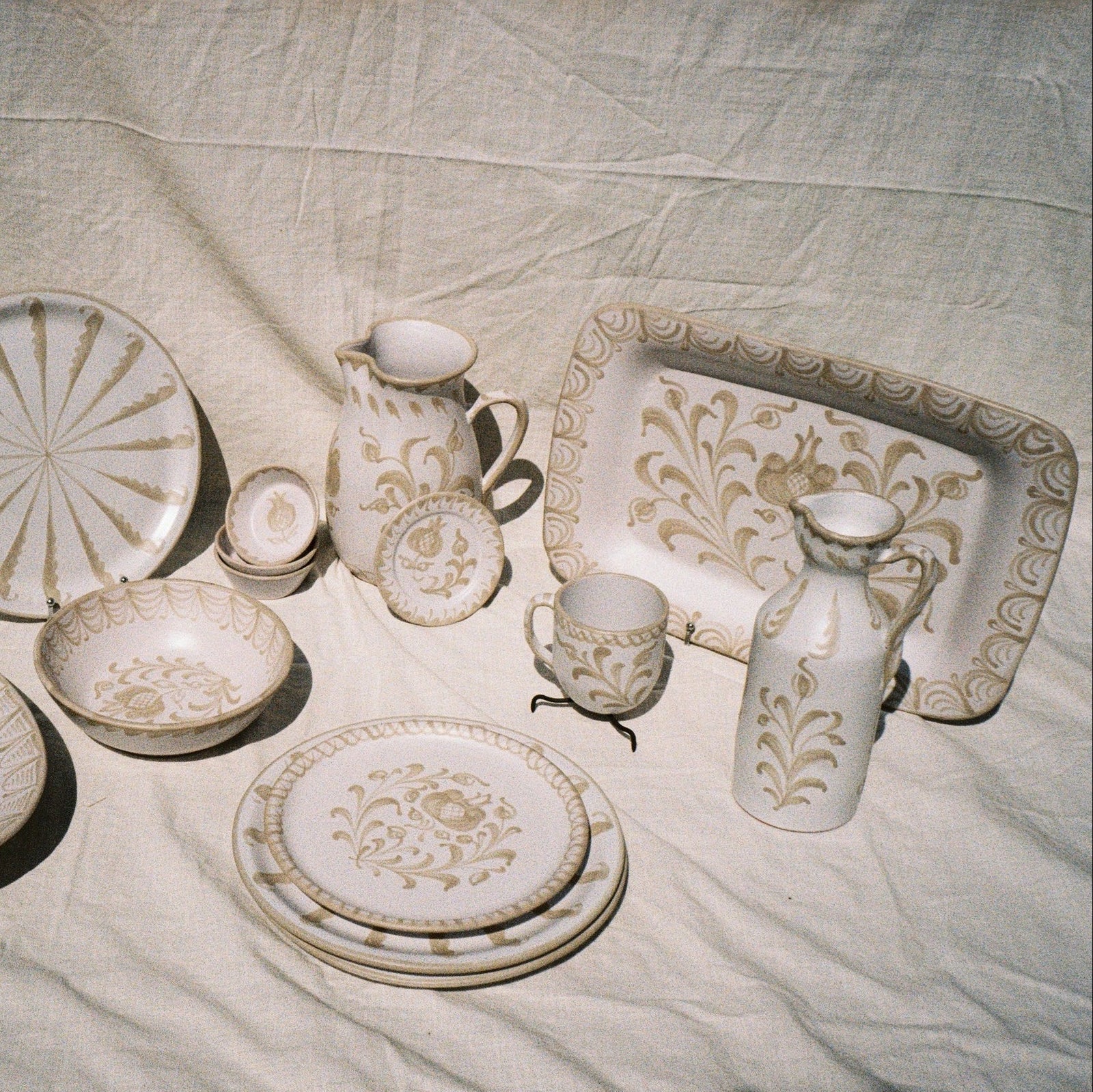 Set of ceramic dishes with floral patterns on a textured fabric background - lifestyle