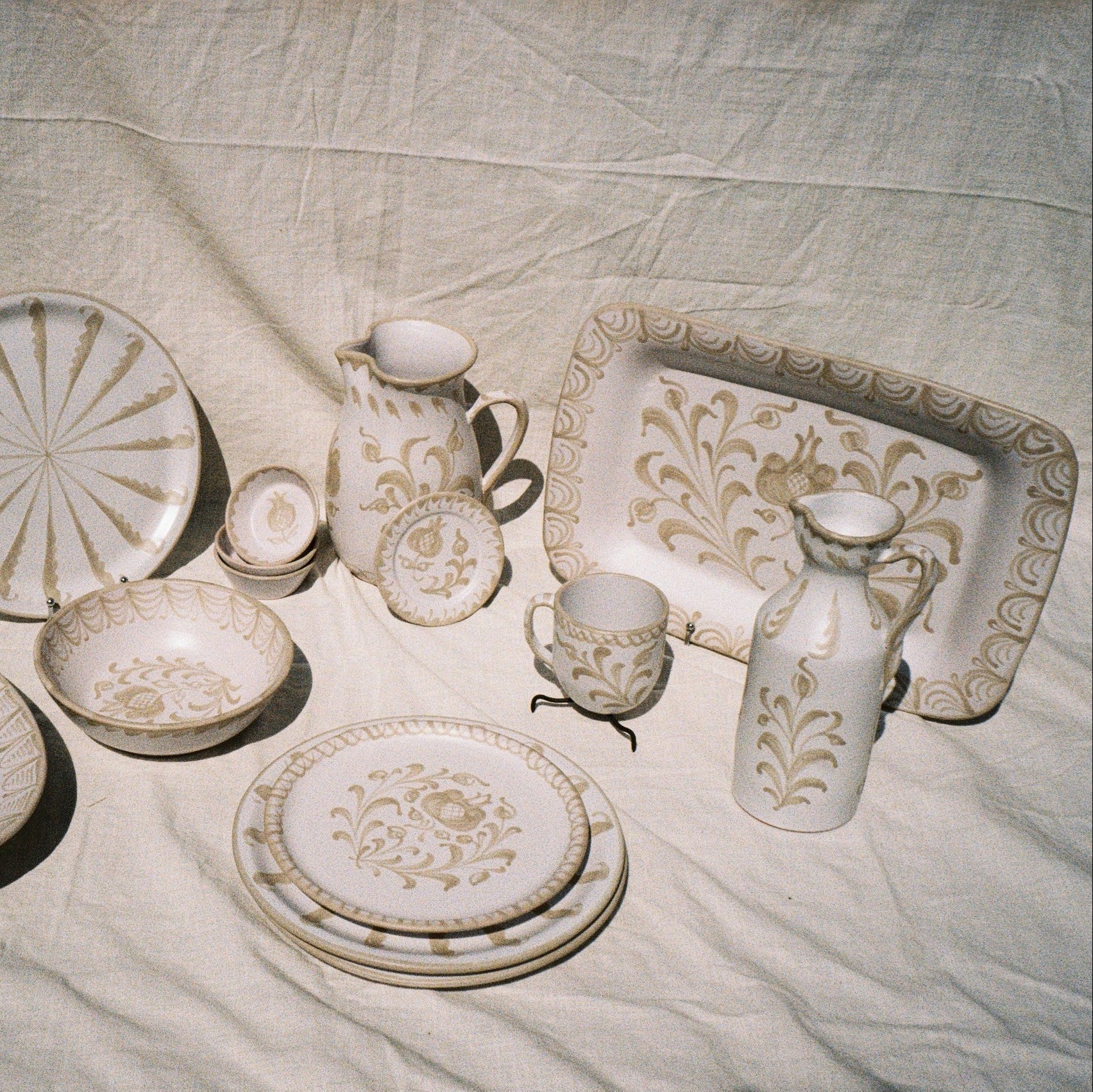 Set of ceramic dishes with floral patterns on a textured fabric background - lifestyle
