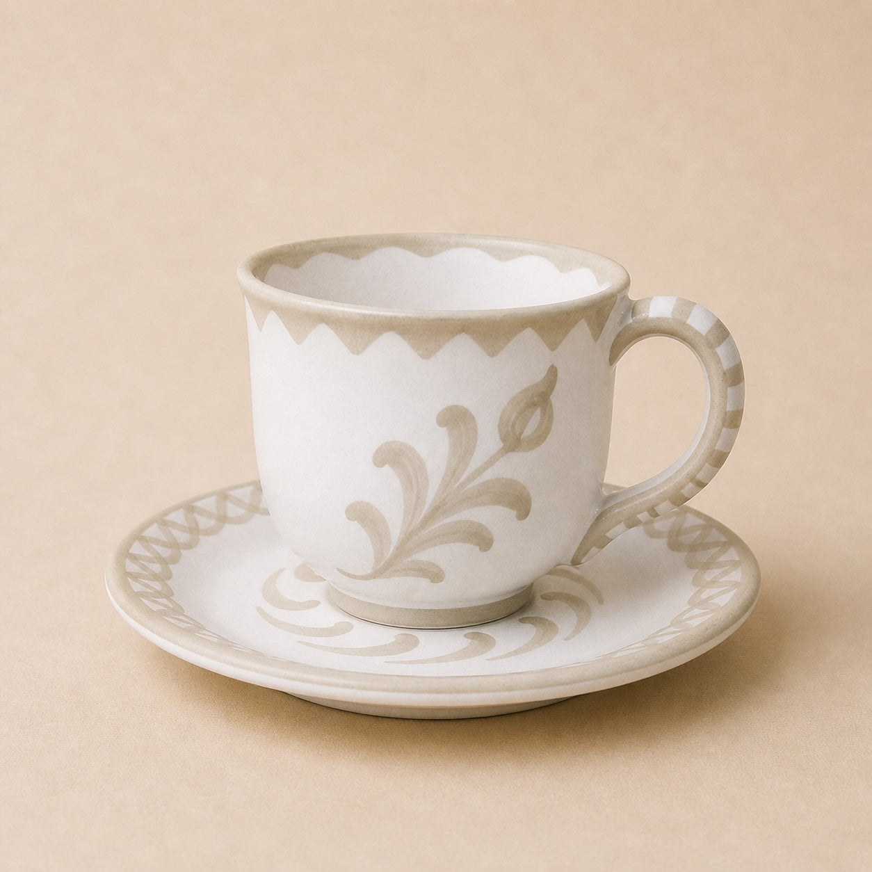 Ceramic cup and saucer with decorative pattern on a beige background