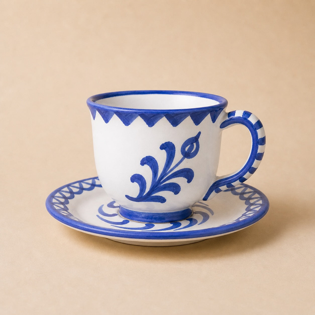 Ceramic cup and saucer with blue floral patterns on a beige background