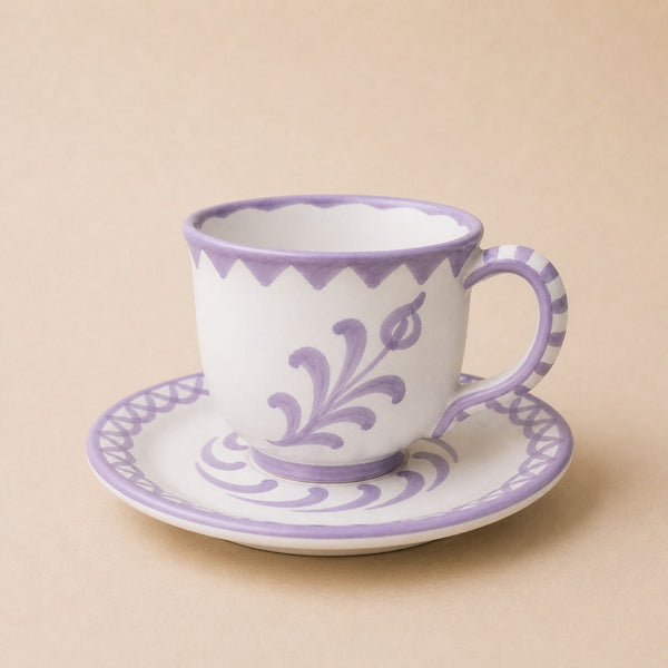 Ceramic cup and saucer with purple floral patterns on a beige background