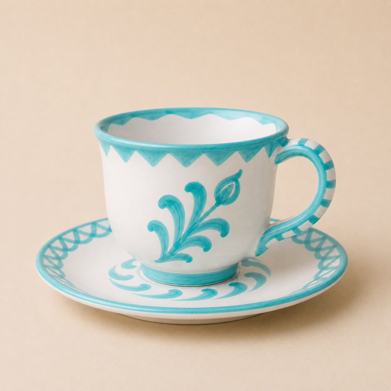 Ceramic cup and saucer with turquoise decorative patterns on a beige background