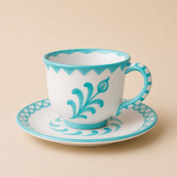 Ceramic cup and saucer with turquoise decorative patterns on a beige background