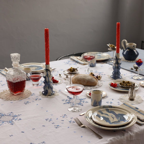 Dining table set for a meal with plates, glasses, and cutlery on a floral tablecloth.  - lifestyle
