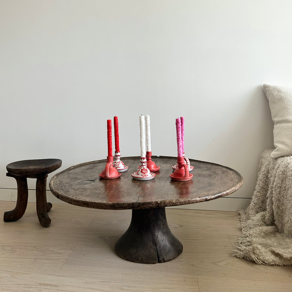 Round wooden table with decorative candle holders in a room setting. - lifestyle