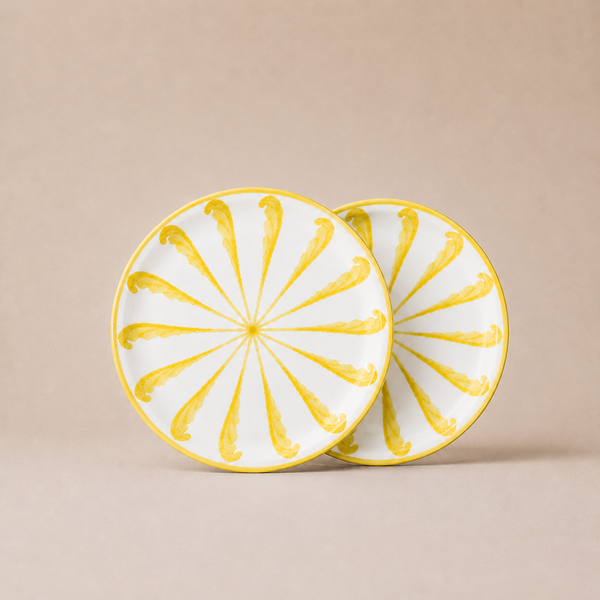 Two ceramic plates with yellow sunburst design on a beige background