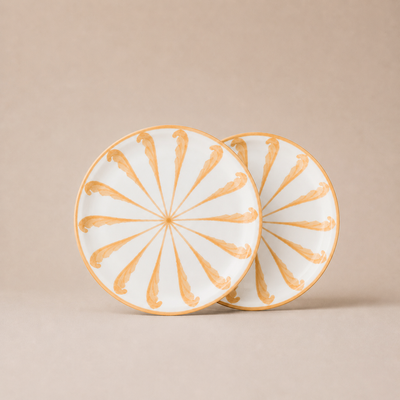 Two ceramic plates with gold decorative patterns on a beige background